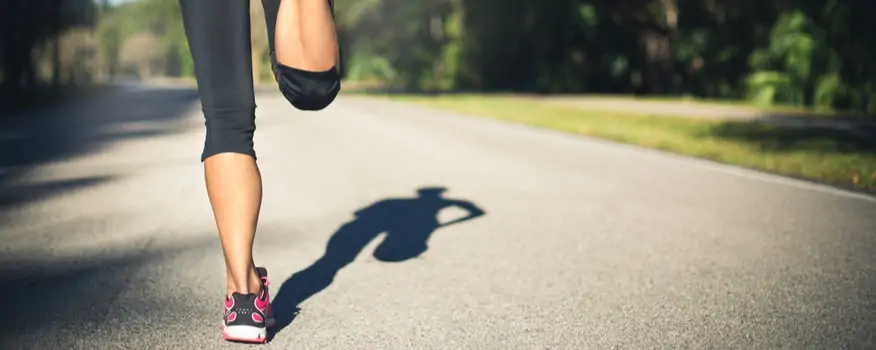 Woman jogging with her shadow on the road