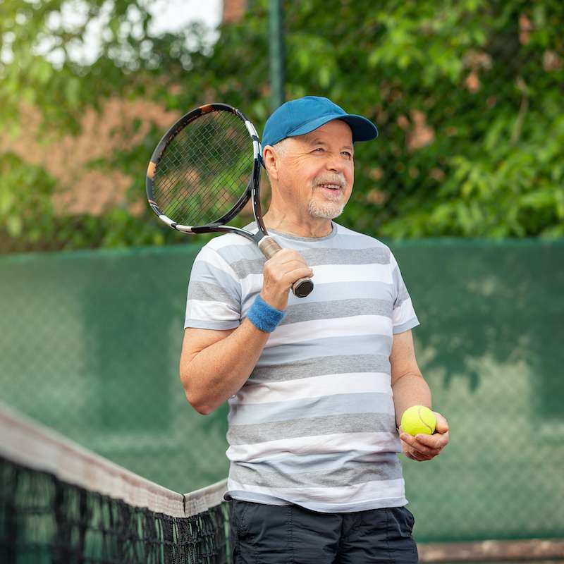 older male playing tennis