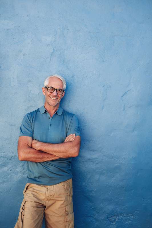 Older male leaning against a blue wall