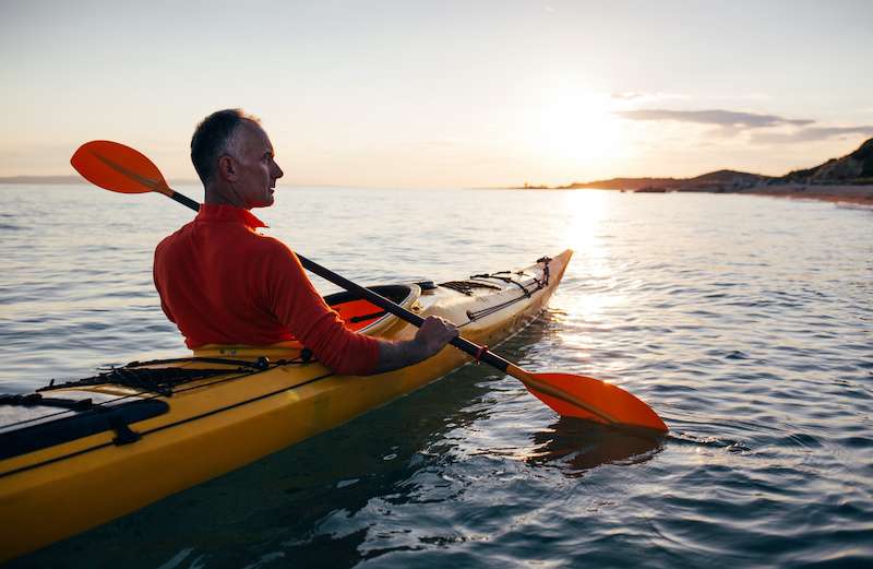 older male paddling a kayak