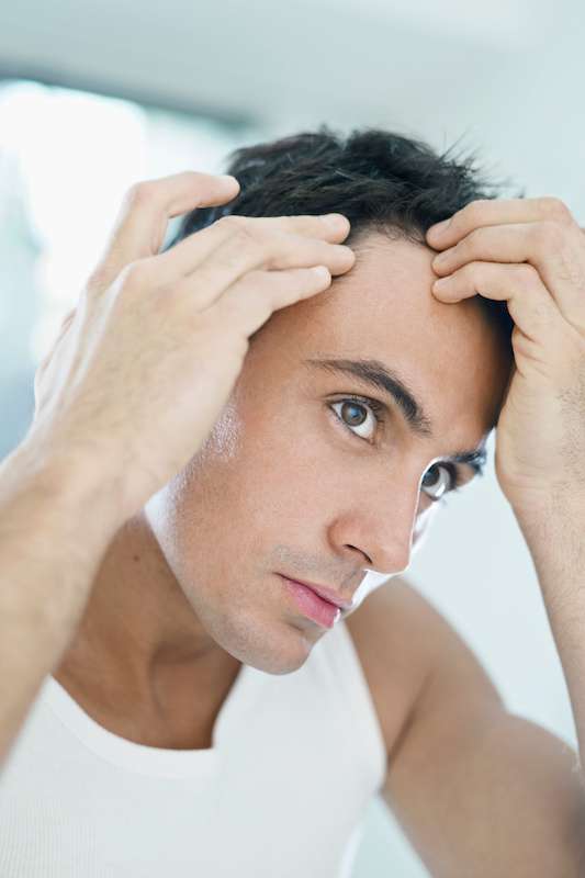 young male examining his thinning hair