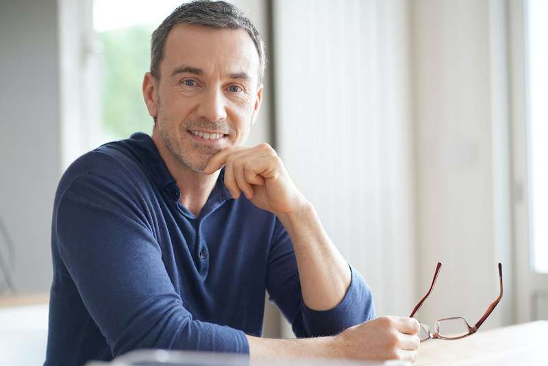 older male smiling with glasses in his hand