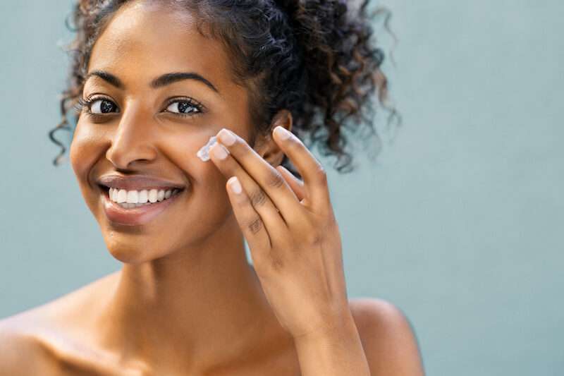 young woman applying cream to her face