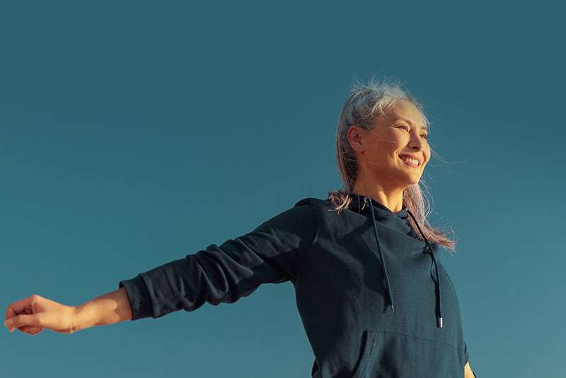 Smiling lady in a sportswear raising arms to the sides