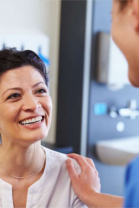 doctor putting hand on smiling patients shoulder red alert screening at forward healthy lifestyles