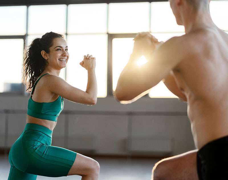 Smiling, handsome woman and man exercising in gym