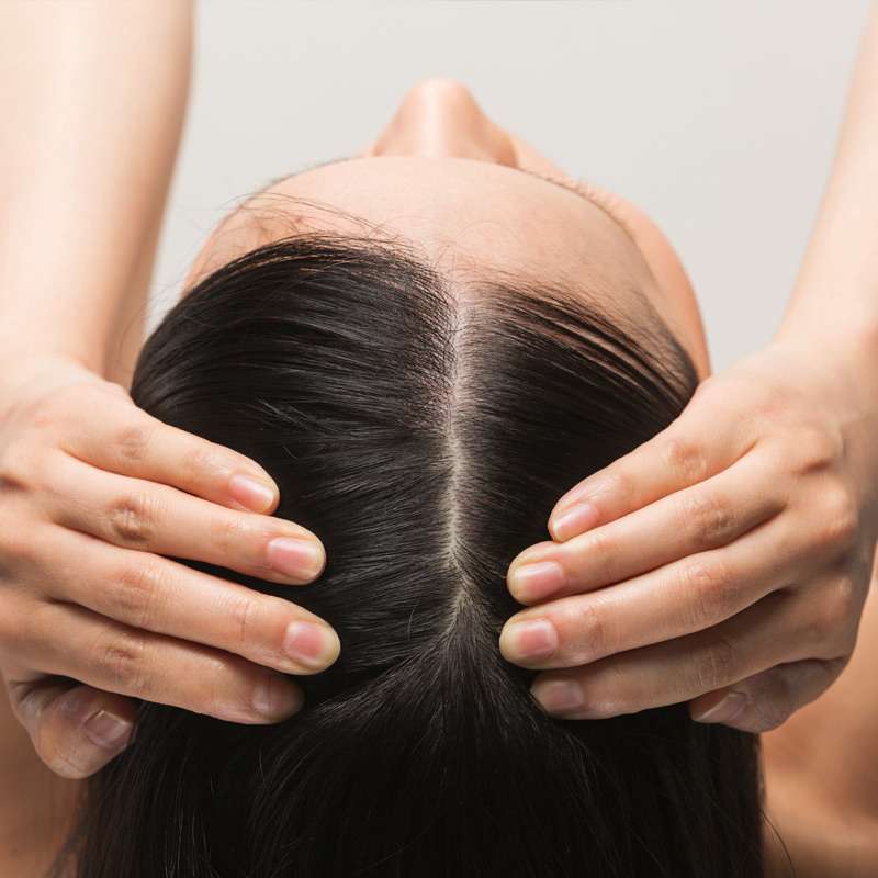 Young woman holding apart her hair line from above