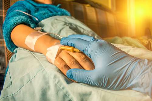 Doctor's gloved hand comforting cancer patient