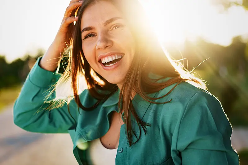 A woman in a green shirt smiles at the camera.